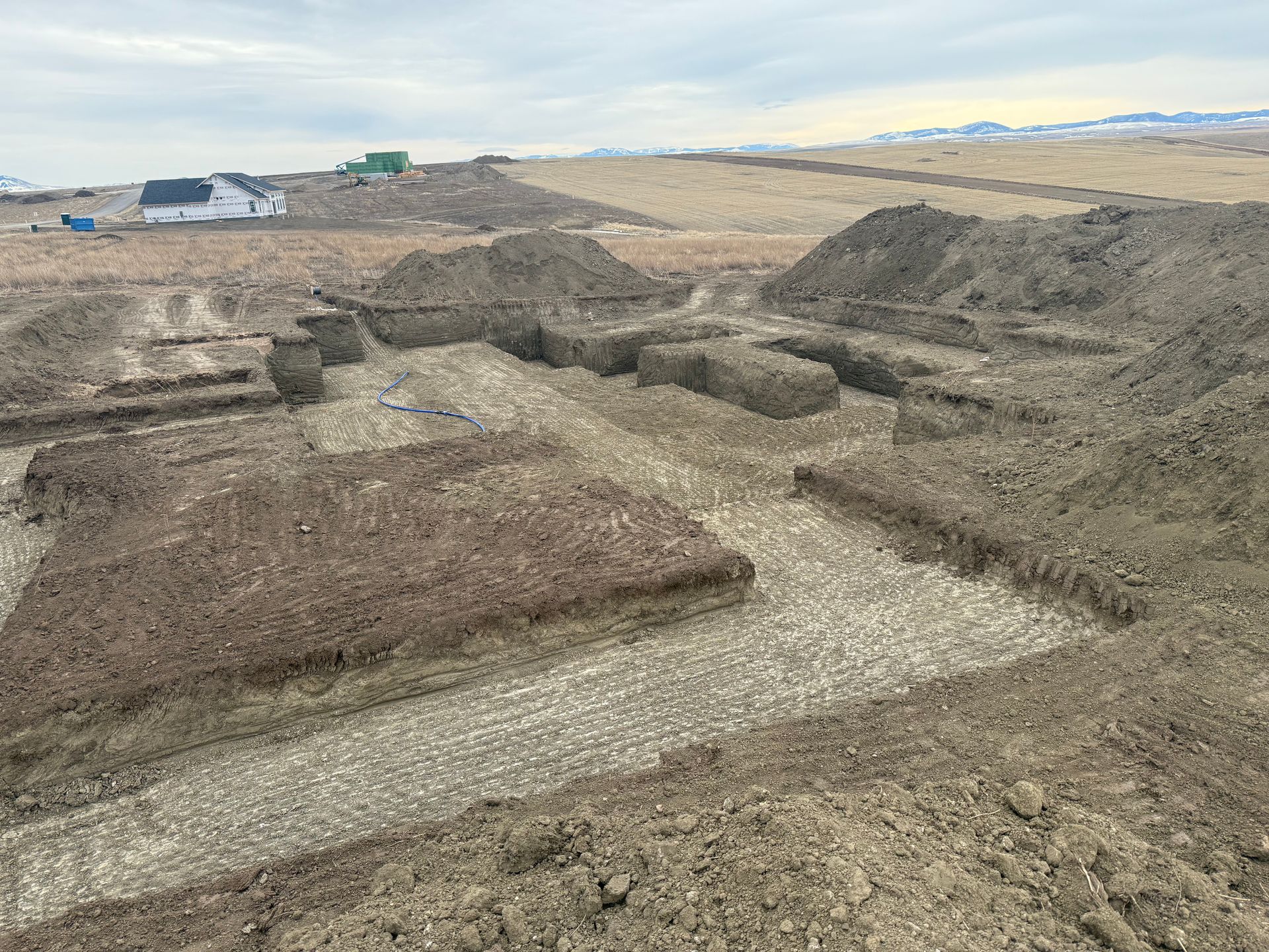 An excavation site for a new building foundation, showing trenches dug into brown earth in a rural, open landscape.