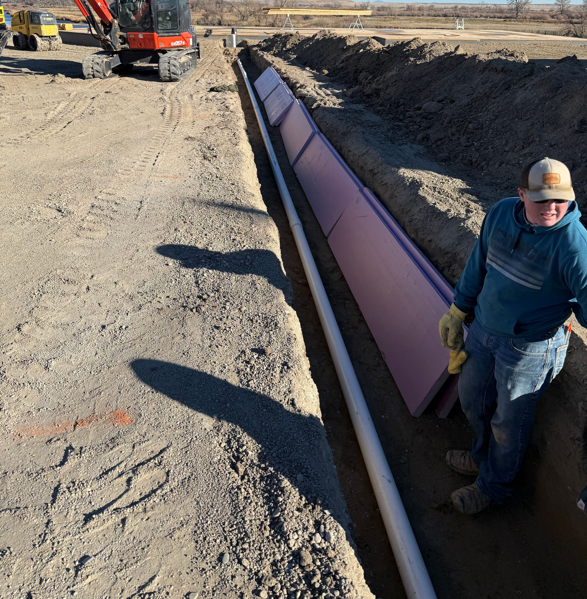 Septic system leach field with black plastic chambers laid in rows over gravel in an open outdoor trench.