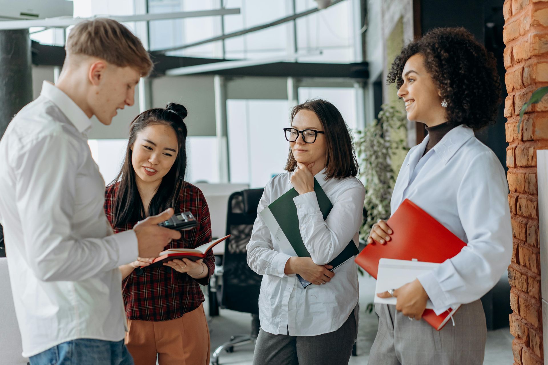 A group of people are standing around talking to each other in an office.