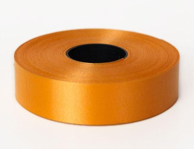 Carrete de cinta de raso naranja sobre una superficie blanca.