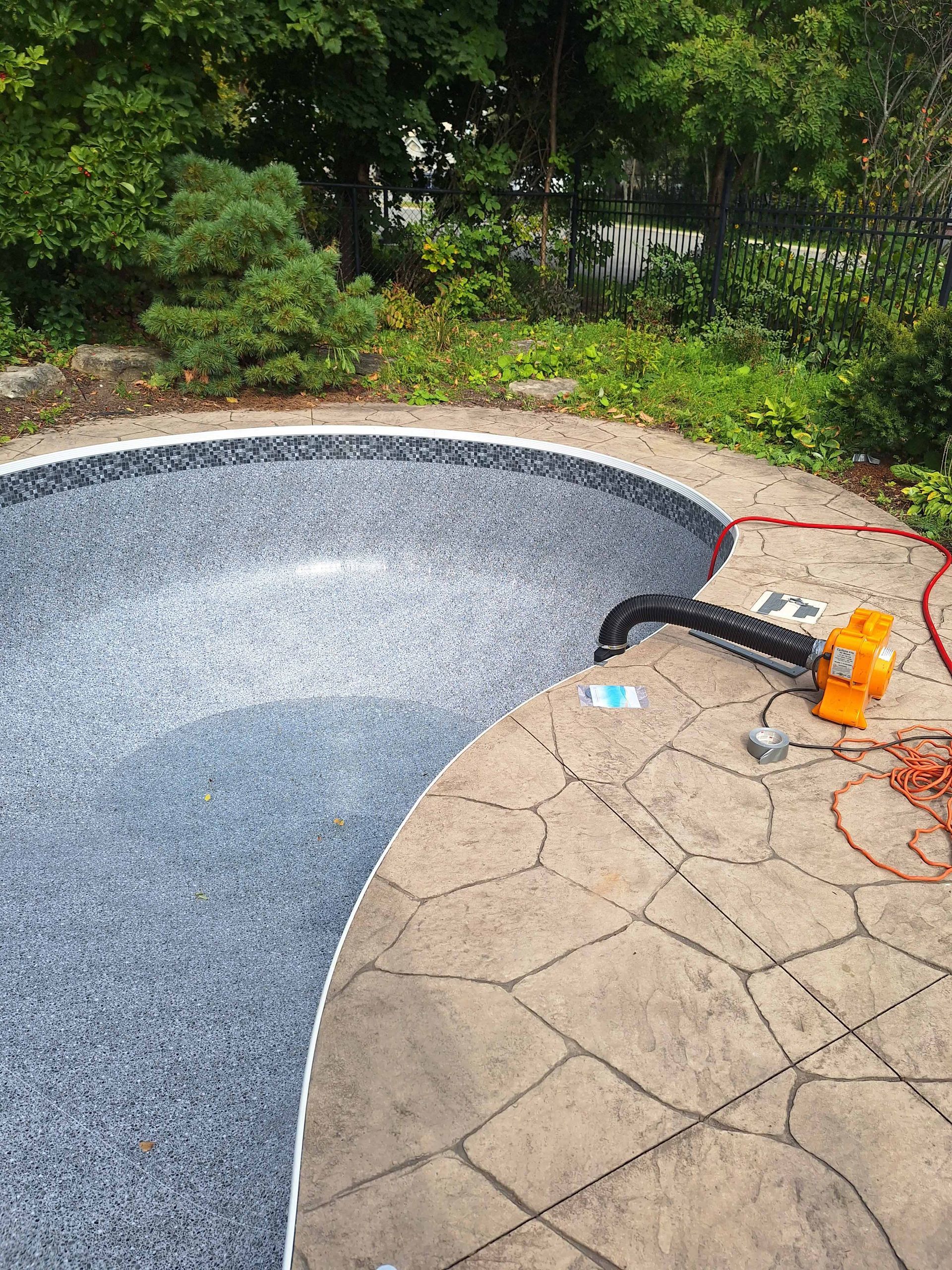 A large swimming pool surrounded by trees and a chair