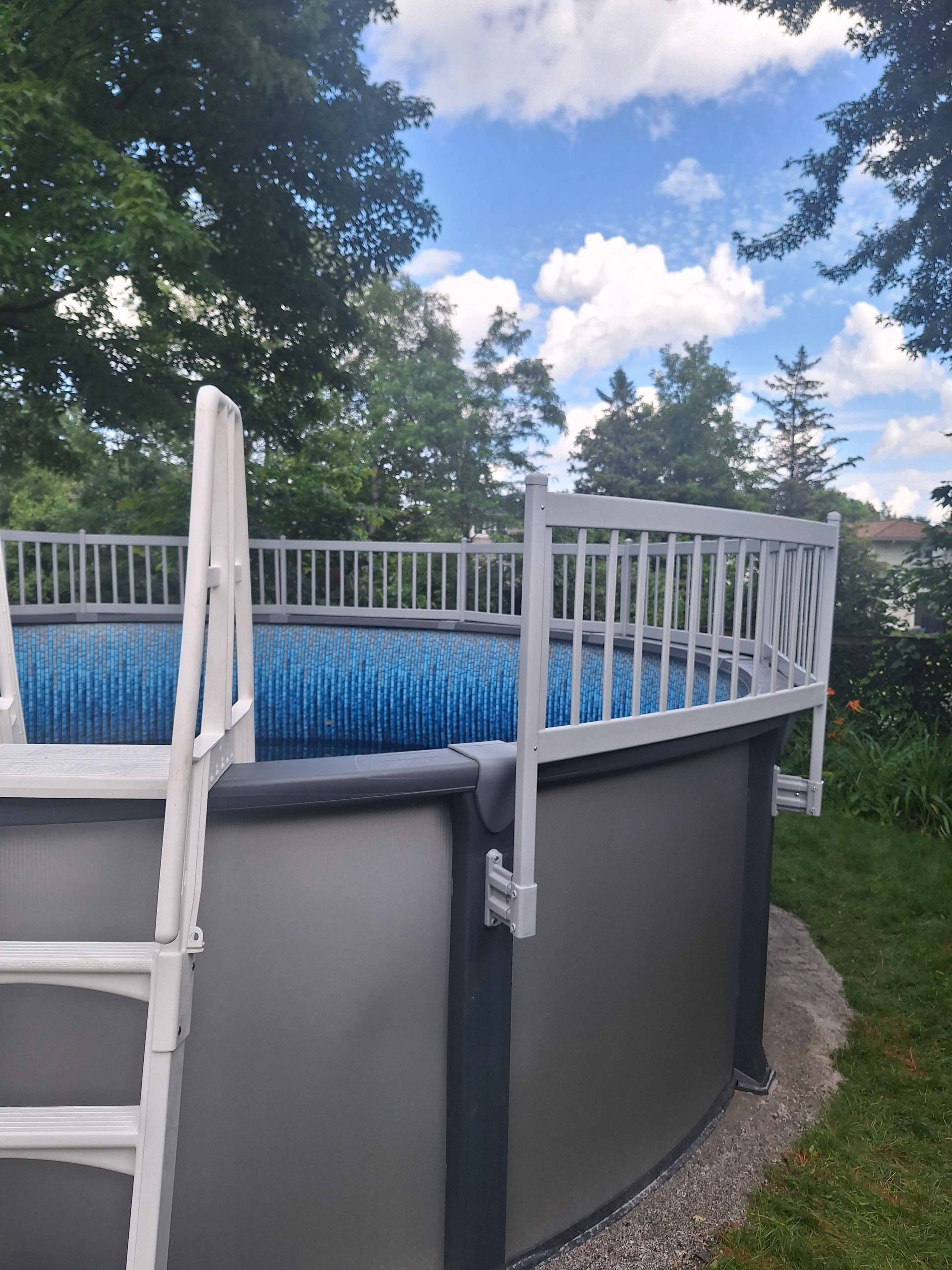 A large swimming pool is surrounded by potted plants and a wooden deck.