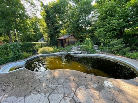 Une piscine vide dans une cour avec un hangar en arrière-plan.