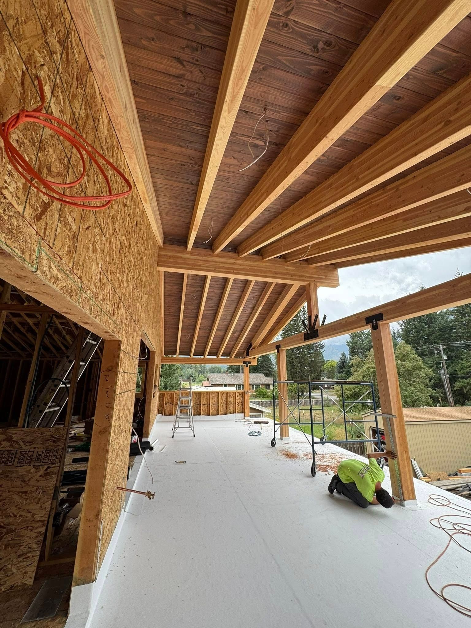 Construction site with wooden beams and a worker in a green vest.