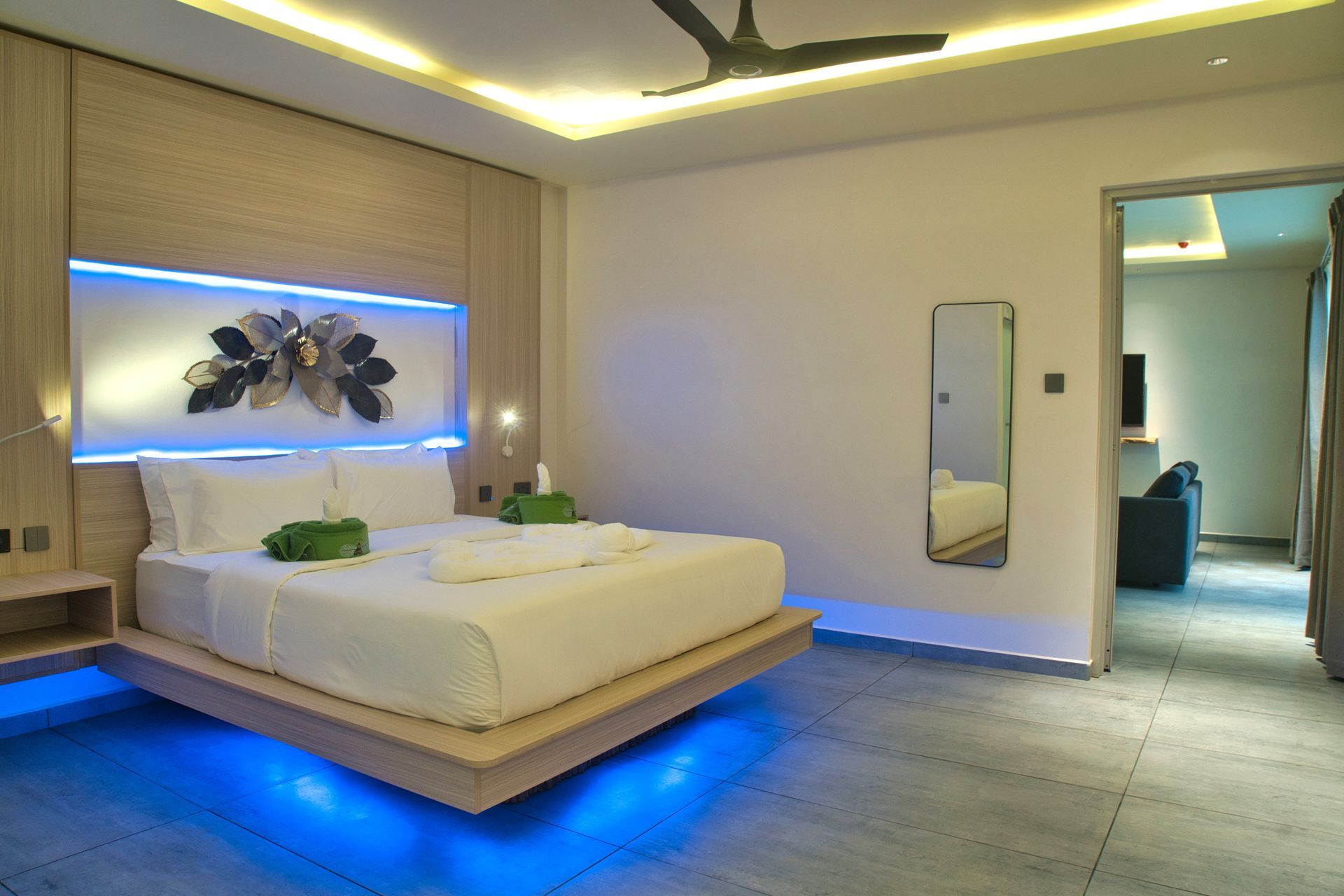 Modern bedroom with floating bed frame, blue LED lighting, and neutral decor.