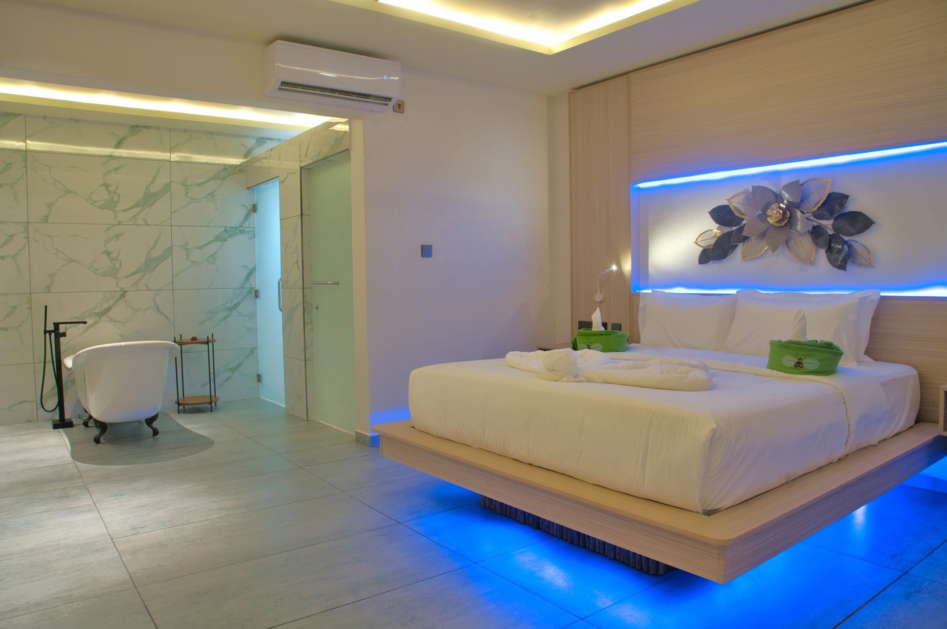 Modern bedroom with a floating bed, bathtub, and blue ambient lighting.