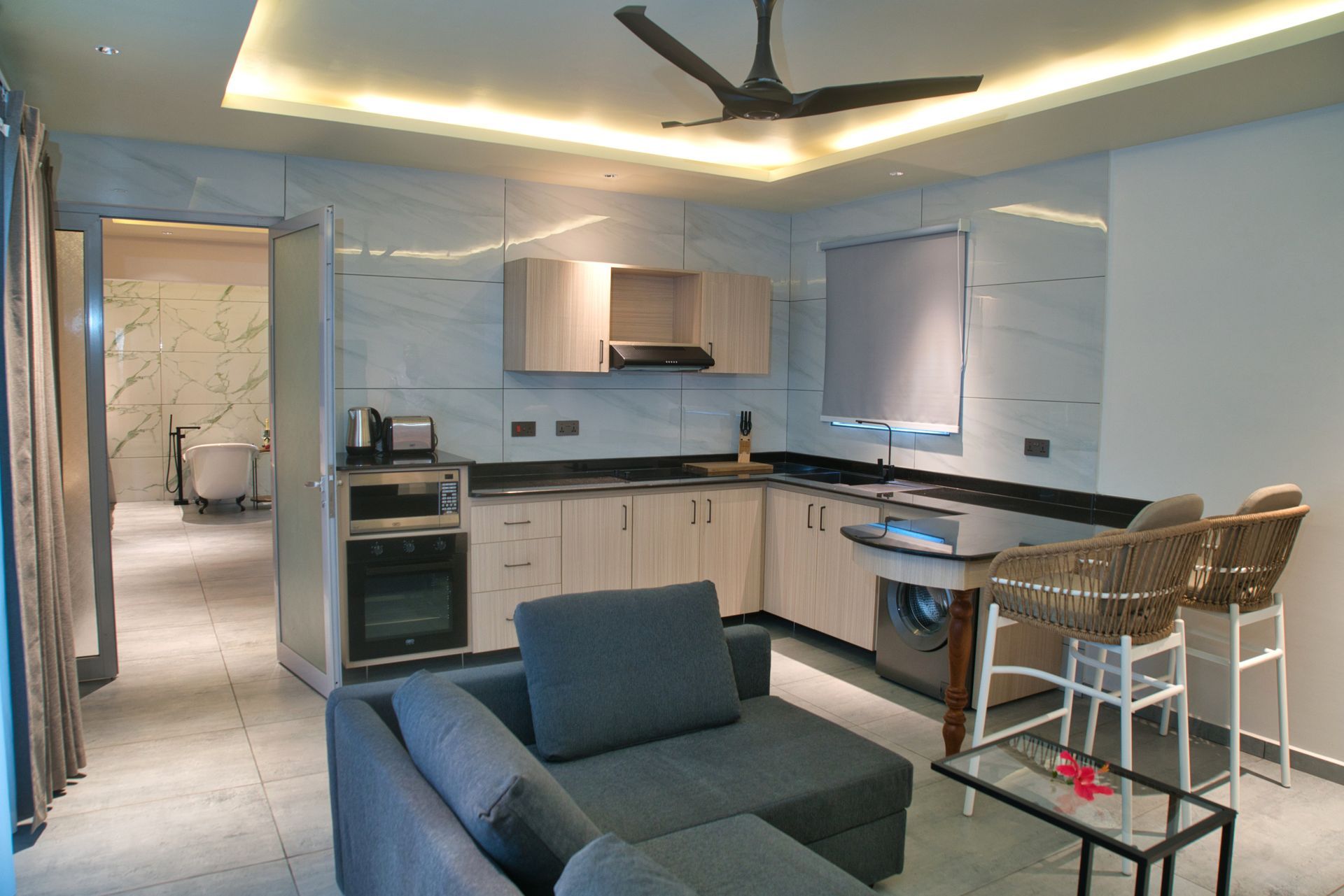 Modern apartment interior with kitchen, living area, and bathroom visible.