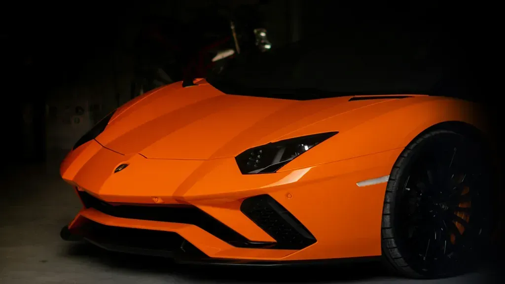 Bright orange sports car parked in a dark garage, symbolizing high performance and rewards.