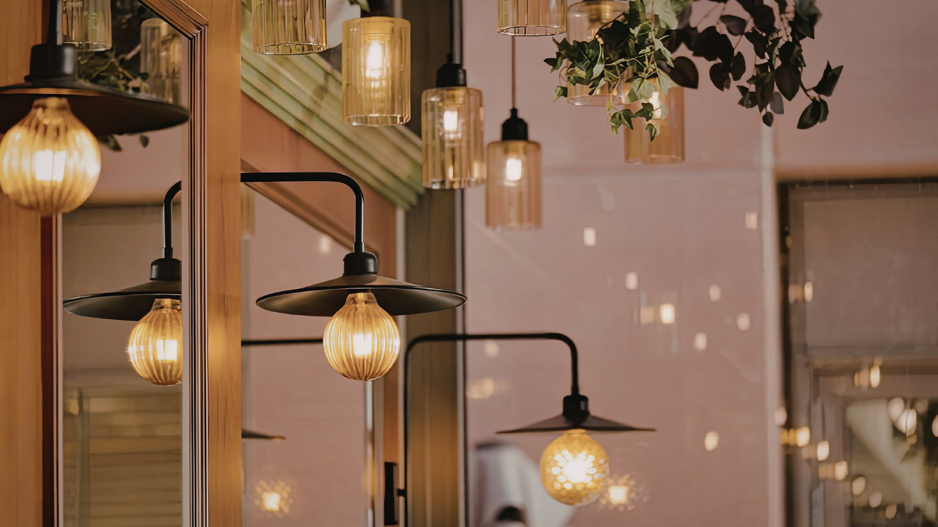 An arrangement of warm, glowing globe pendant lights and industrial-style wall sconces in a softly lit interior space.