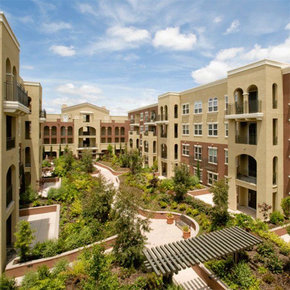 A large apartment building with a lush green courtyard in front of it