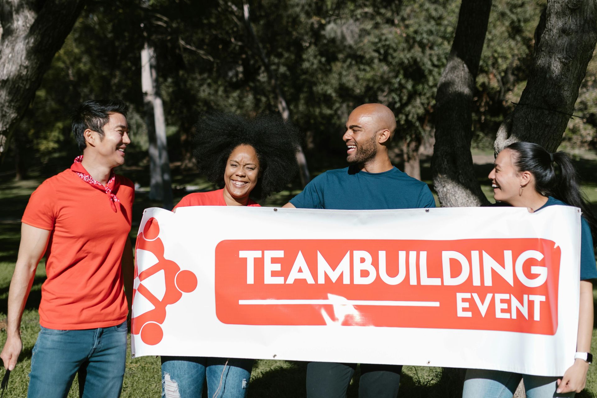 Four people stand outdoors holding a white banner that says 