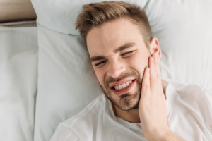 A man is laying in bed with a toothache.