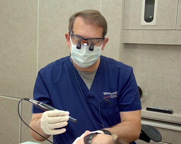 A dentist wearing a mask and glasses is examining a patient 's teeth