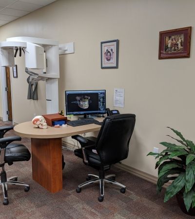A dental office with a table , chairs , and a computer.