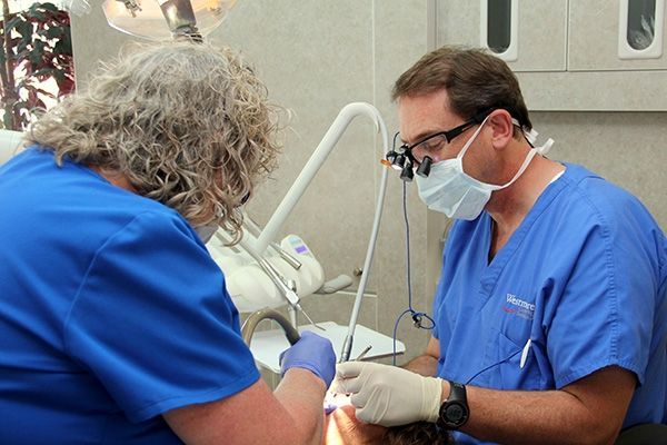 A dentist and a nurse are working on a patient 's teeth.
