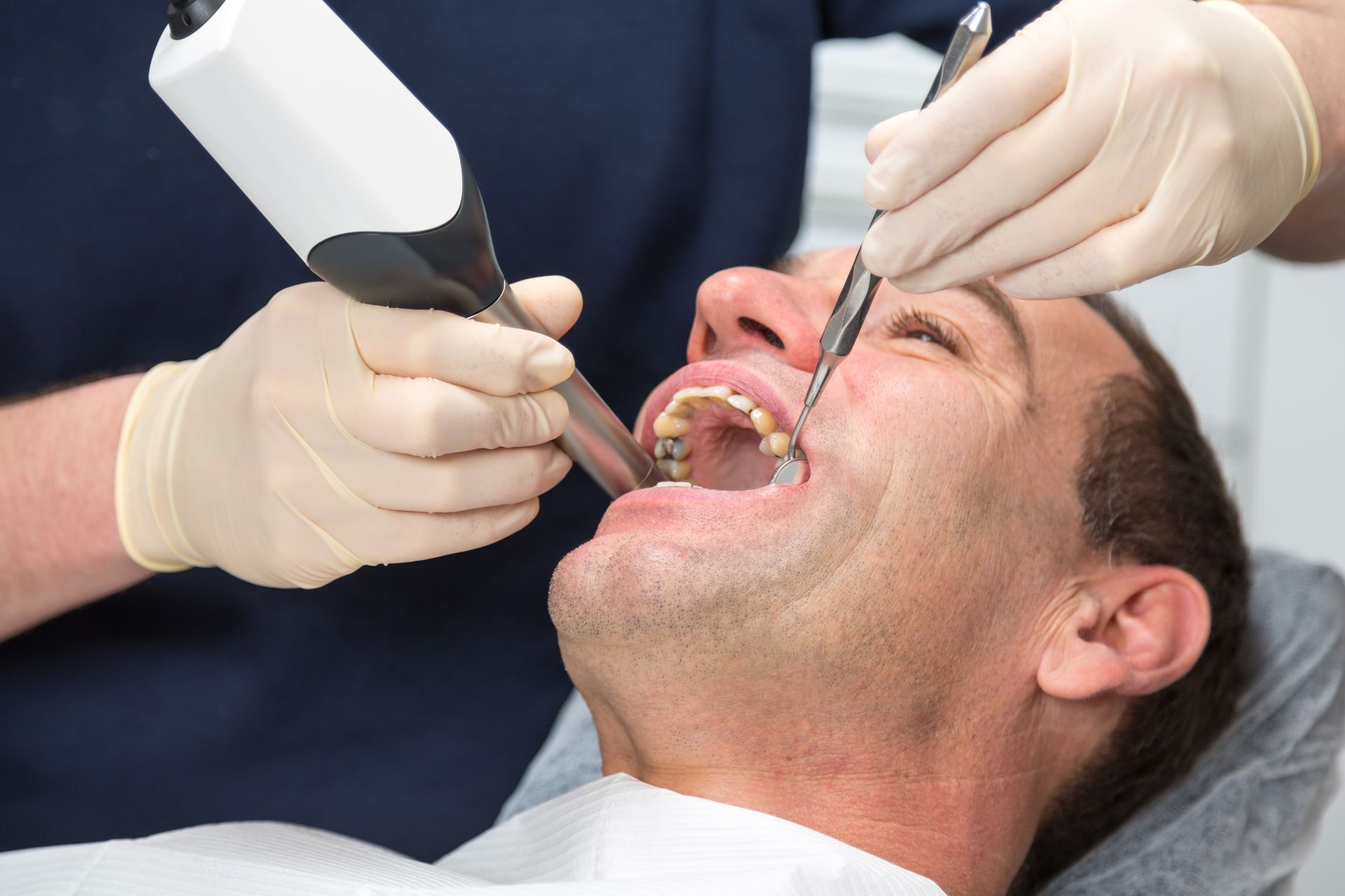 A man is getting his teeth examined by a dentist.