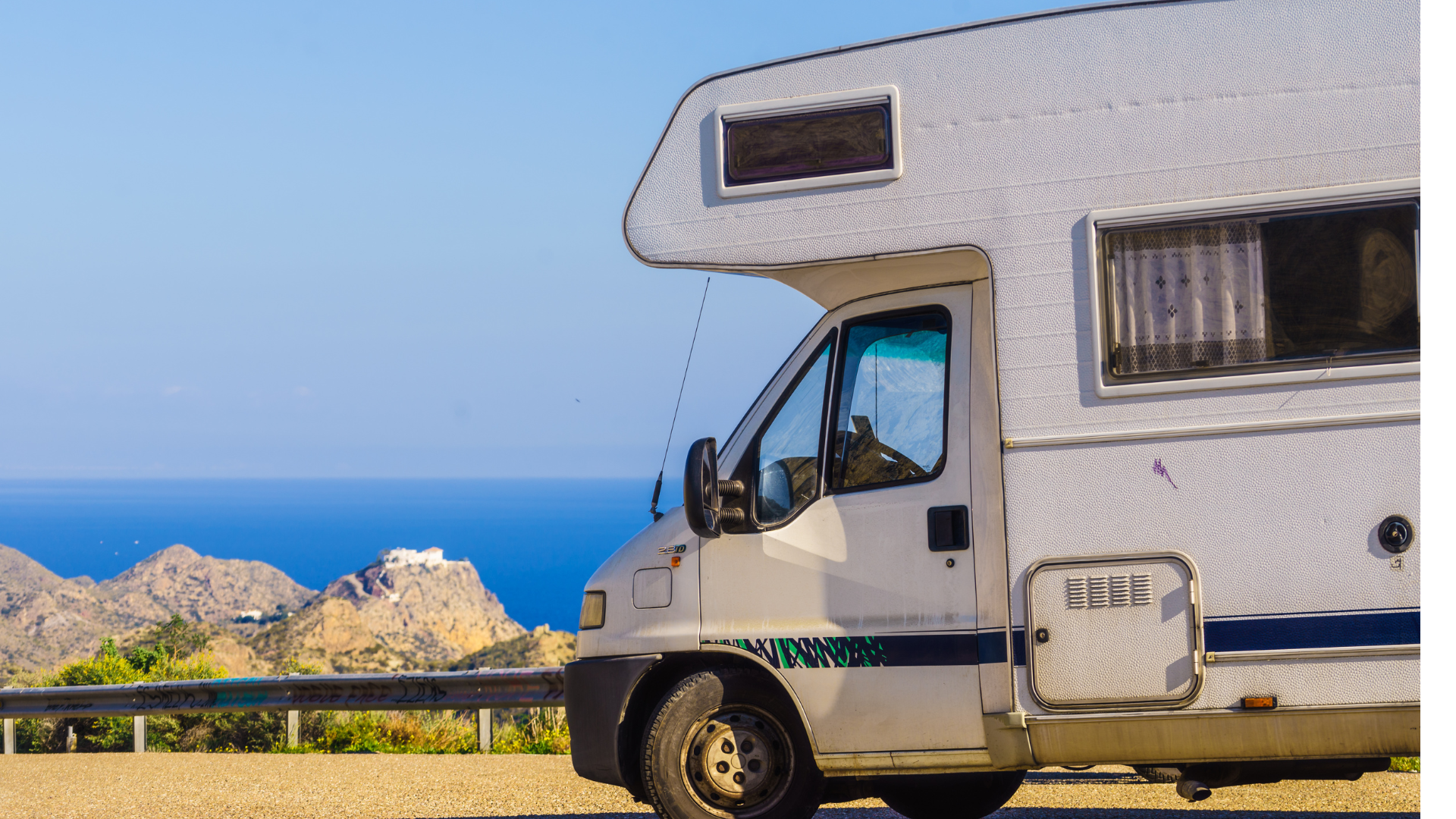 White RV parked overlooking a scenic coastal view.