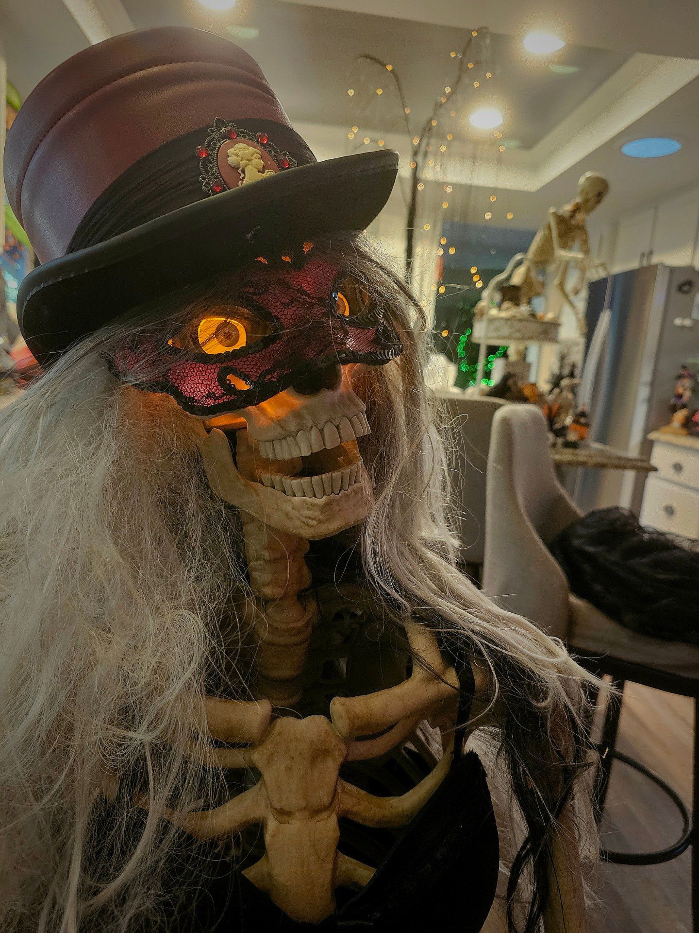A skeleton wearing a top hat and a mask is standing in a room.