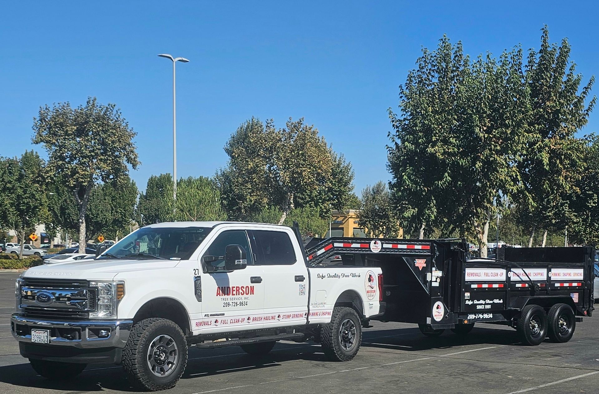 A white truck with a trailer attached to it is parked in a parking lot.