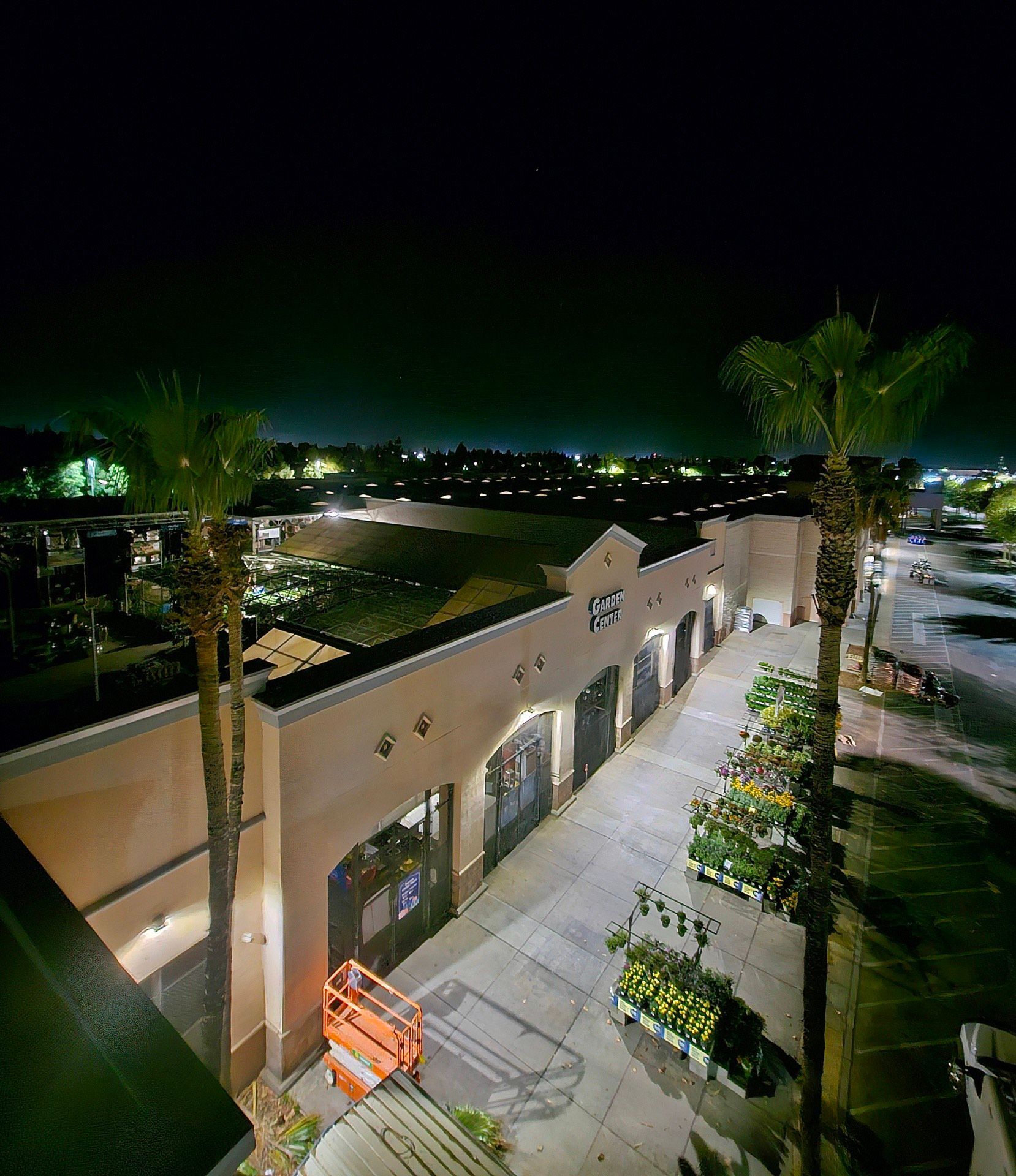 An aerial view of a building at night with palm trees in front of it