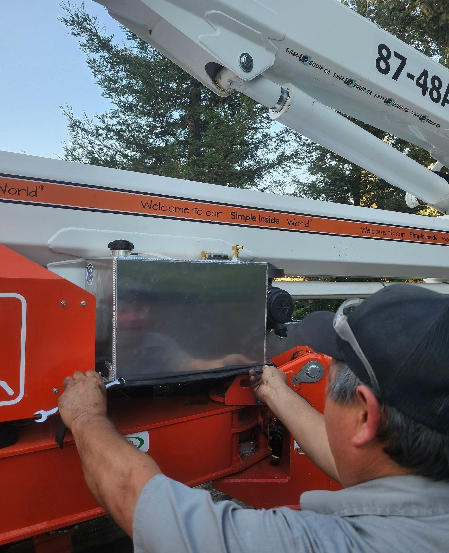 A man is working on a crane with the number 87 on it