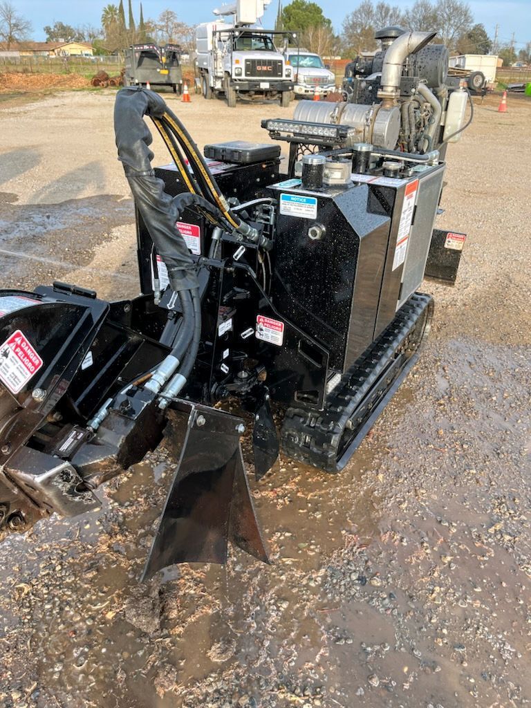 A black machine is sitting in the middle of a dirt field.