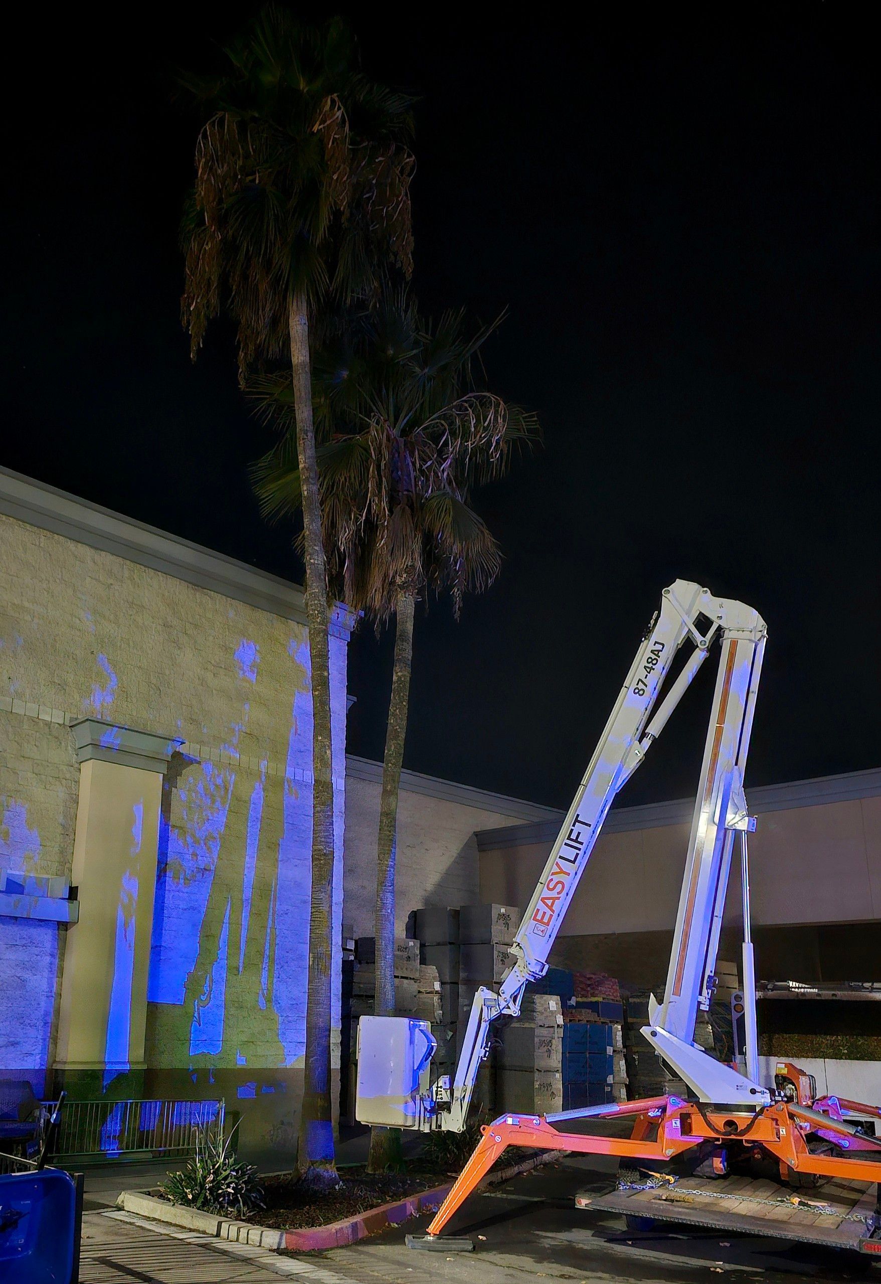 A crane is parked in front of a building at night.