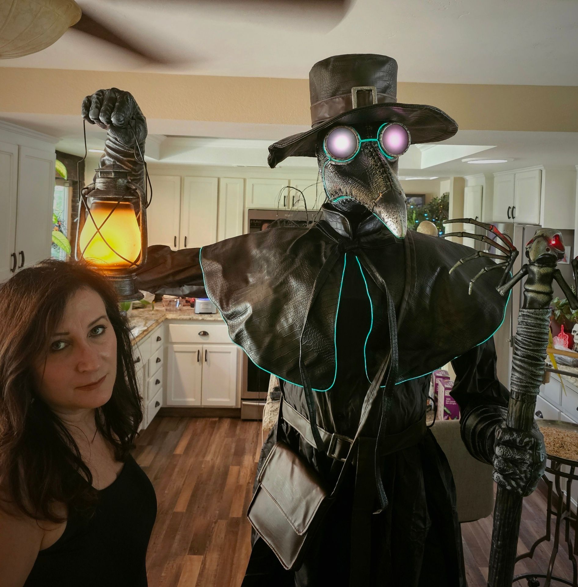A woman stands next to a plague doctor holding a lantern