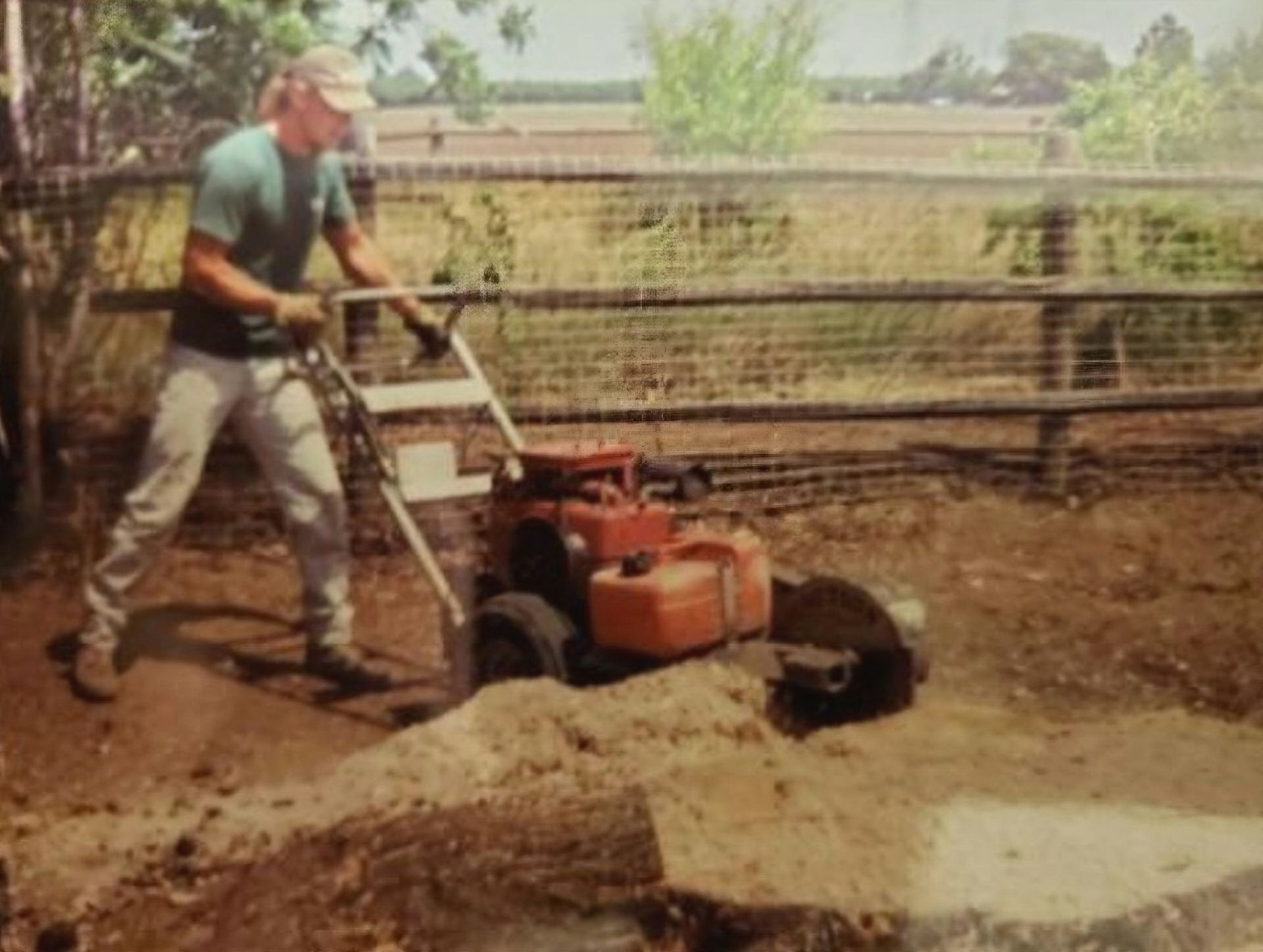 A man is using a small tractor to dig a hole in the ground.