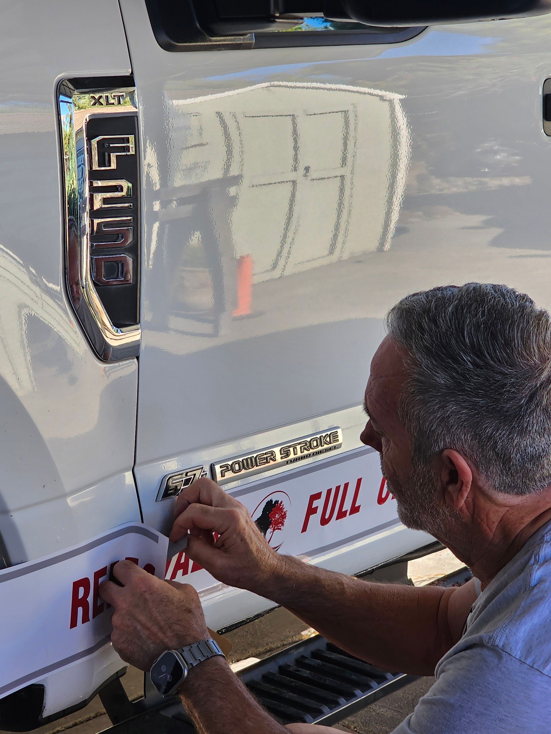 A man is working on the back of a ford truck