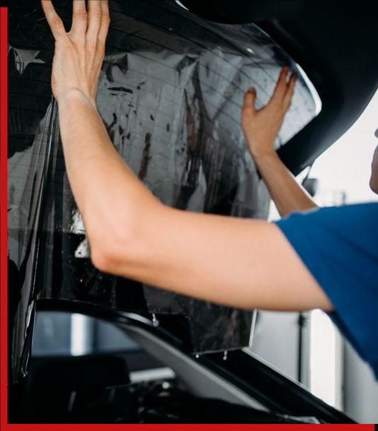 A person is covering a car window with a black film A person is covering a car window with a black film