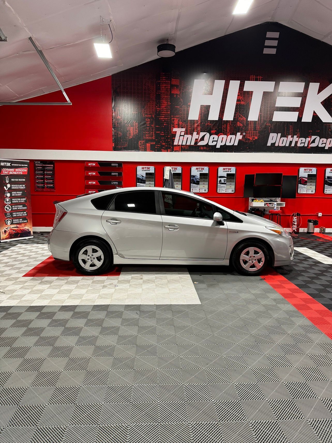 A silver prius is parked in a car dealership.