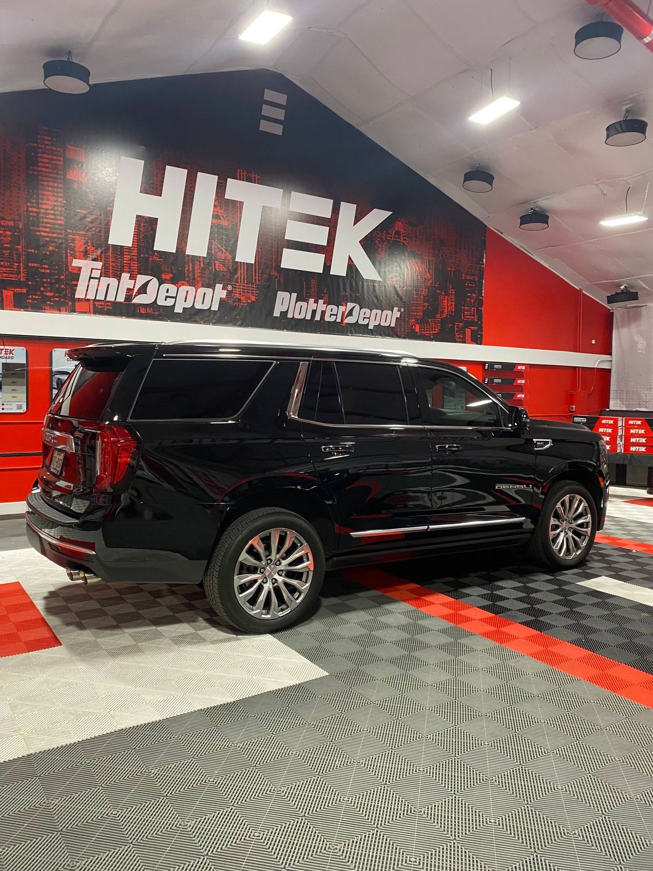 A black suv is parked in a garage with a sign on the wall.