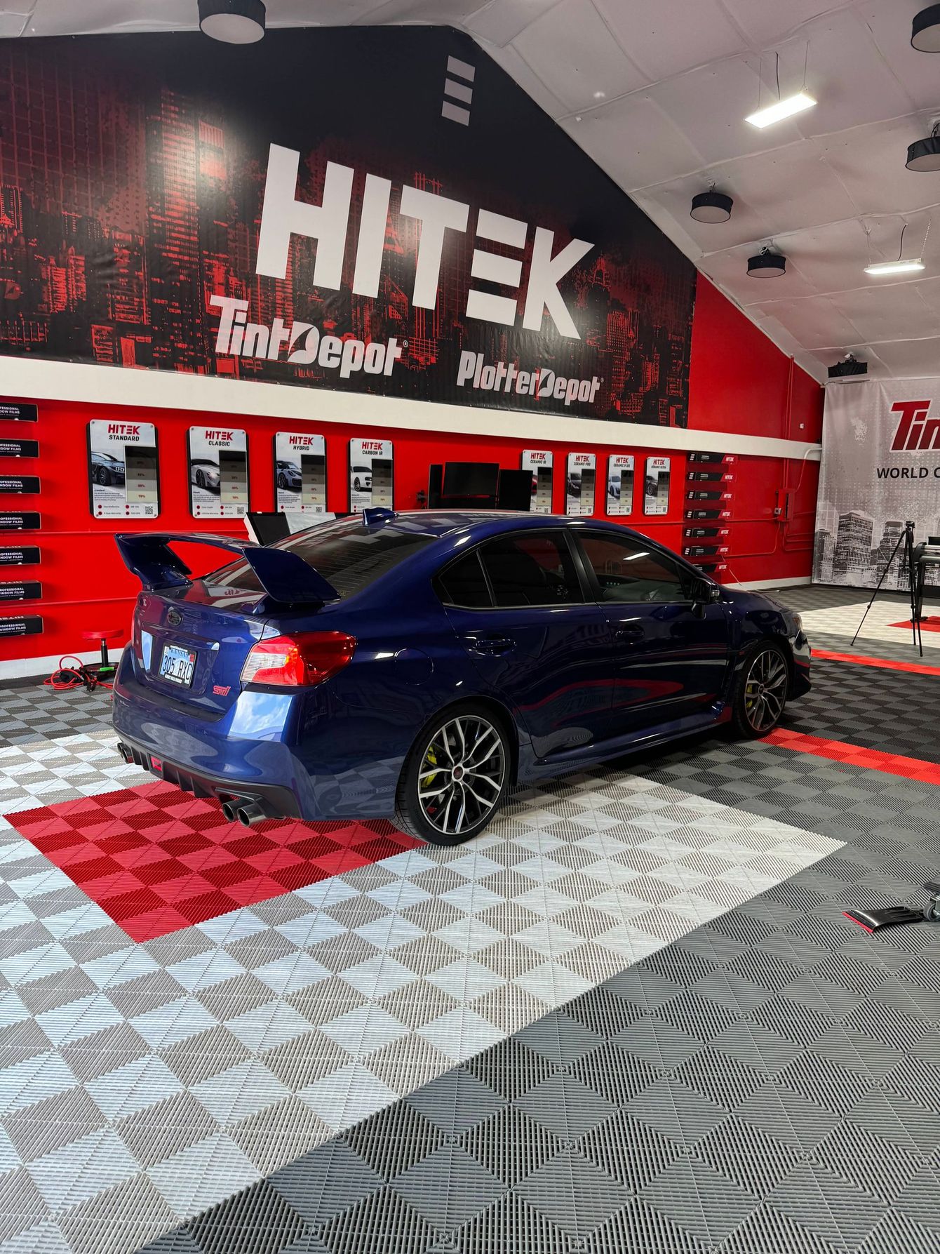 A blue car is parked in a car wash in a garage.