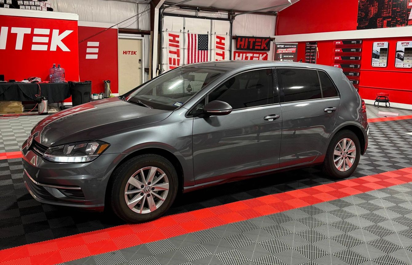 A gray volkswagen golf is parked in a garage.