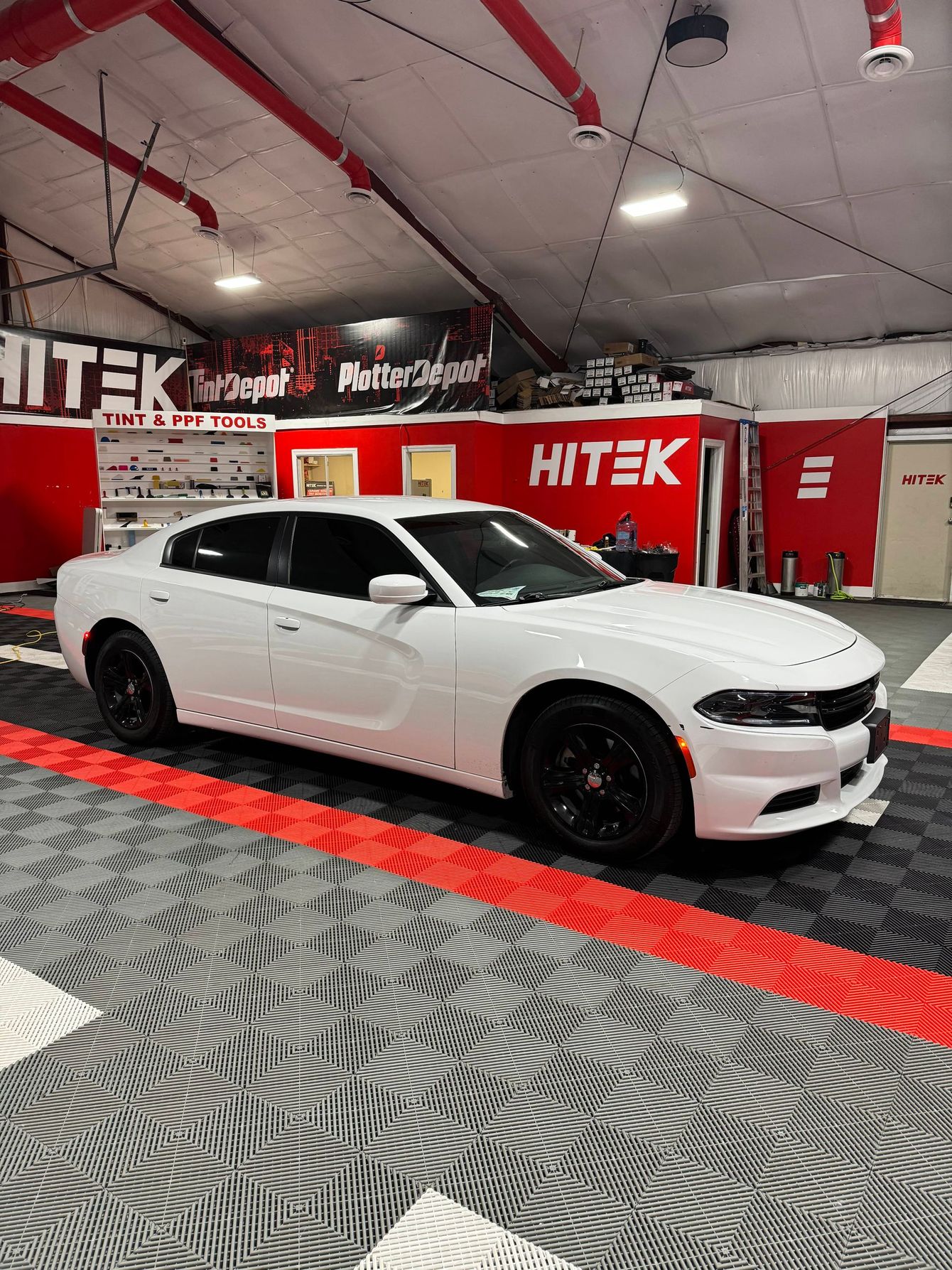 A white dodge charger is parked in a garage.