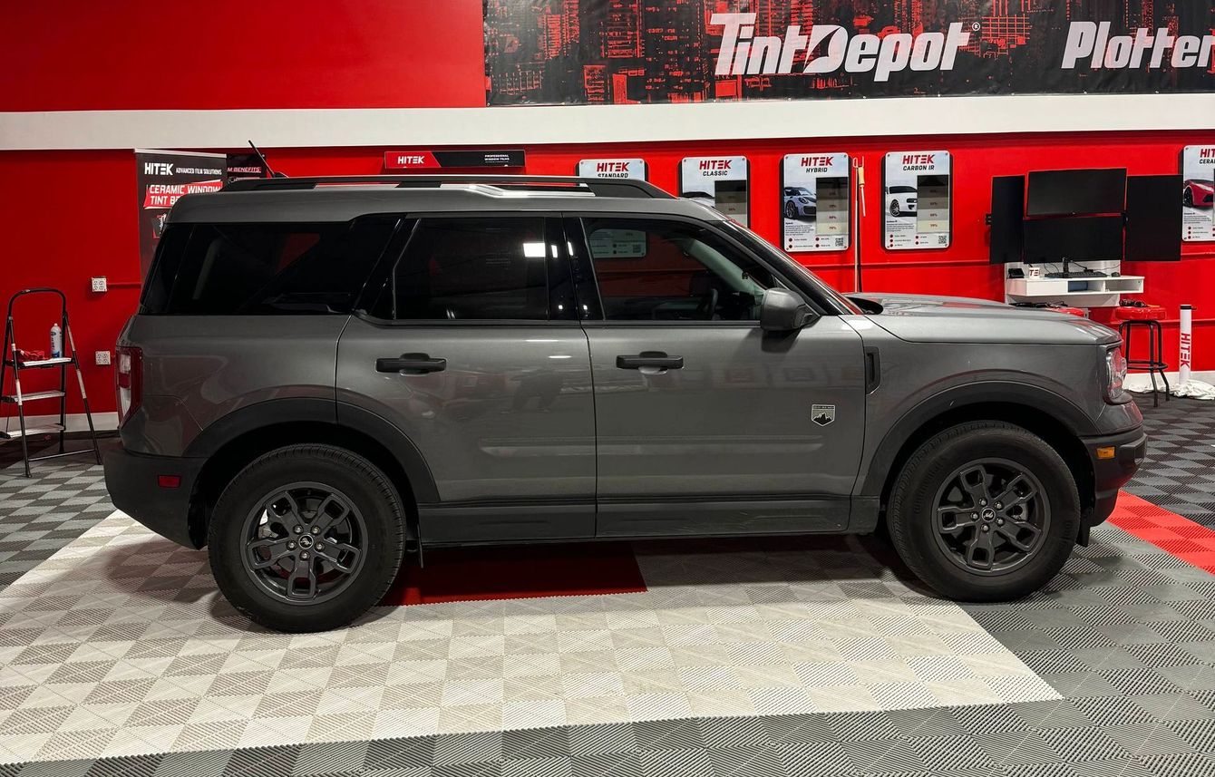 A gray ford bronco sport is parked in a showroom.