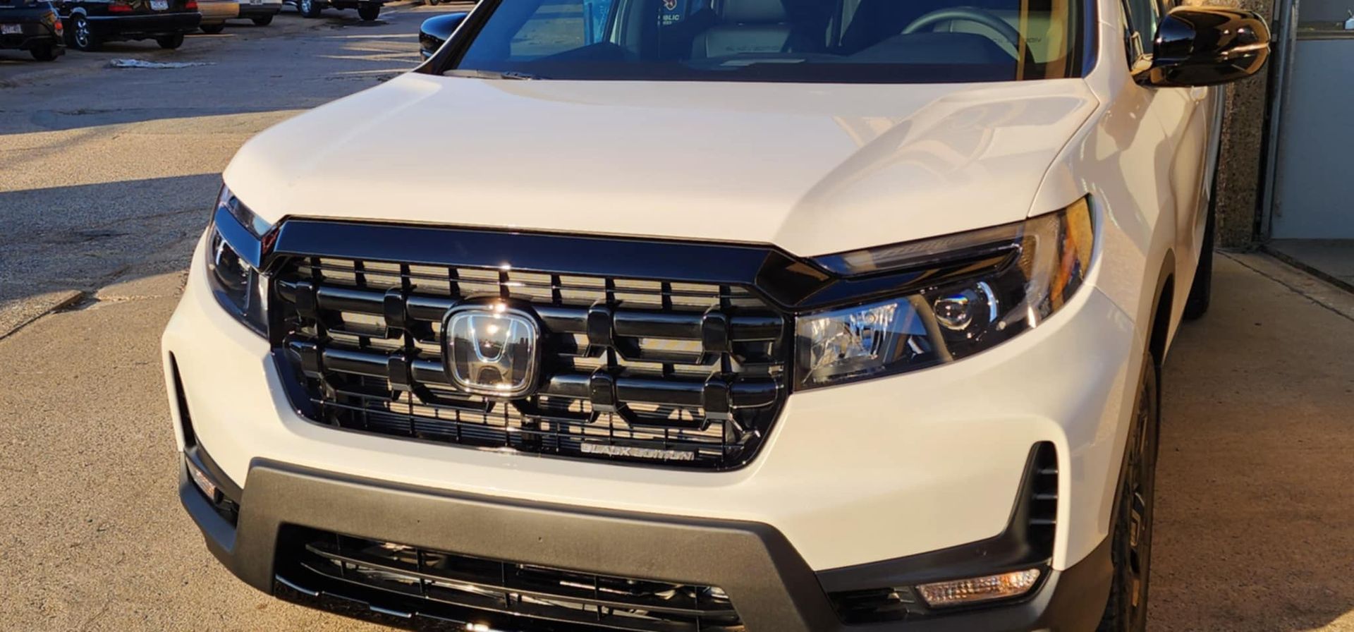 A white pickup truck with a black grille is parked in a parking lot.