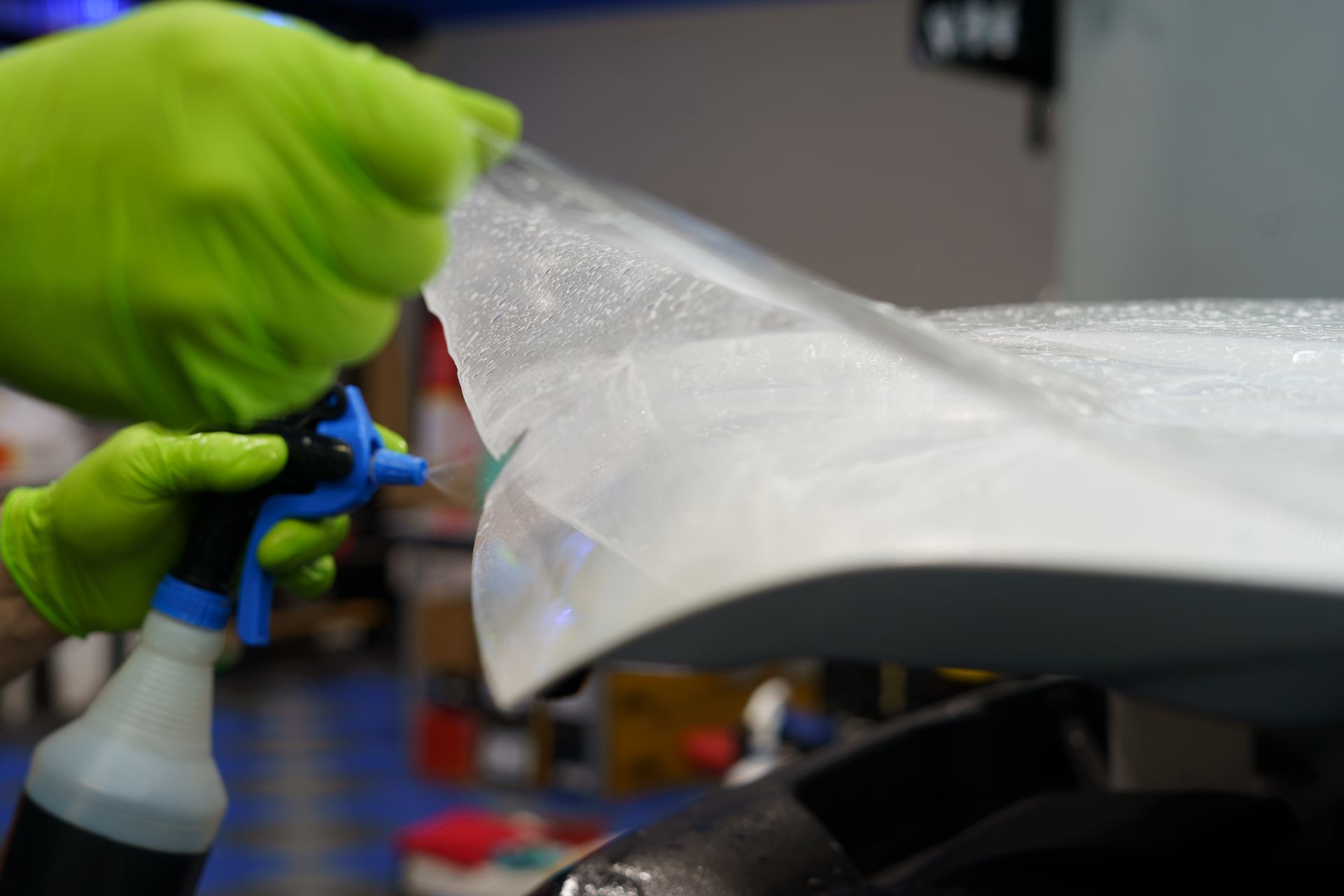 A person is spraying a car with a spray bottle.