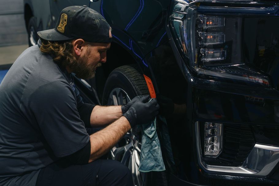 A man is working on the front of a black truck.