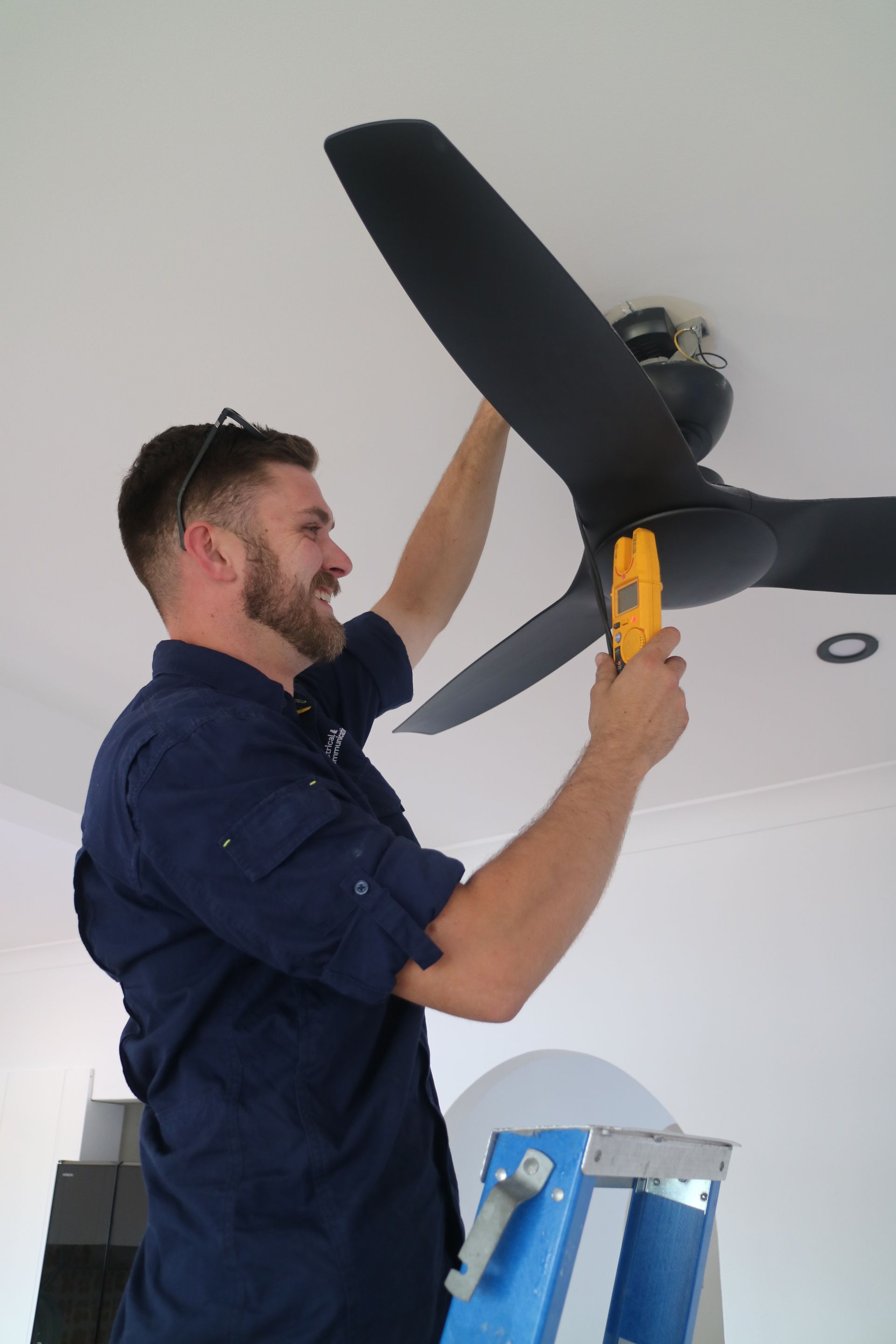 An Electrician Testing A Ceiling Fan— TB Electrical & Communications in Erina, NSW