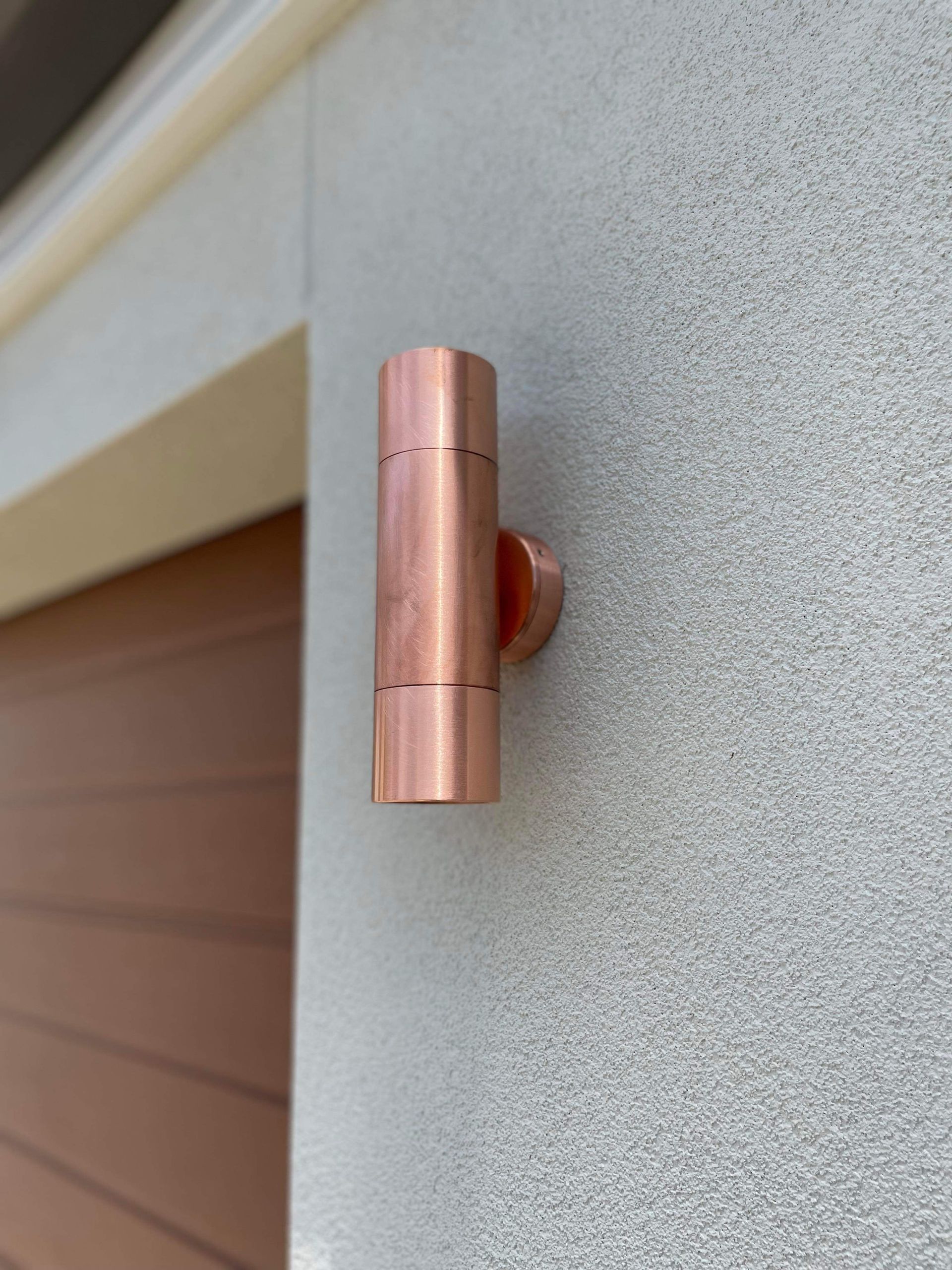 An Outdoor Light Fixture On A Garage Wall In Copper — TB Electrical & Communications in Erina, NSW