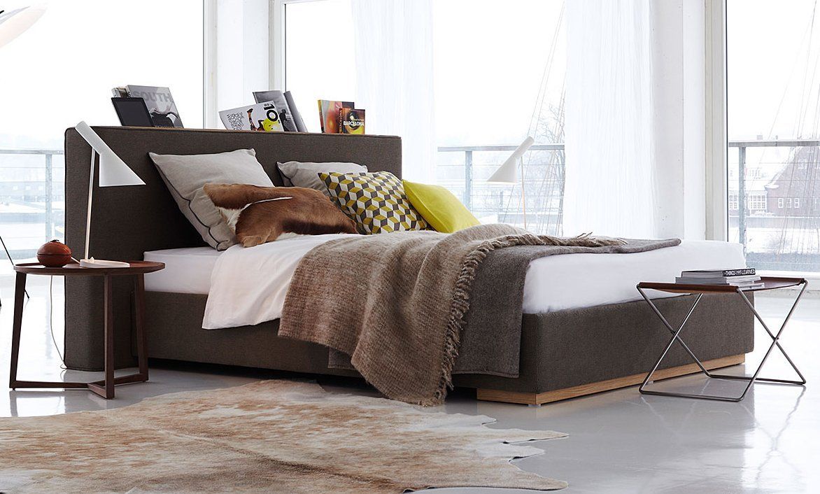 Ansicht auf braunes Bett mit Decke und Kissen