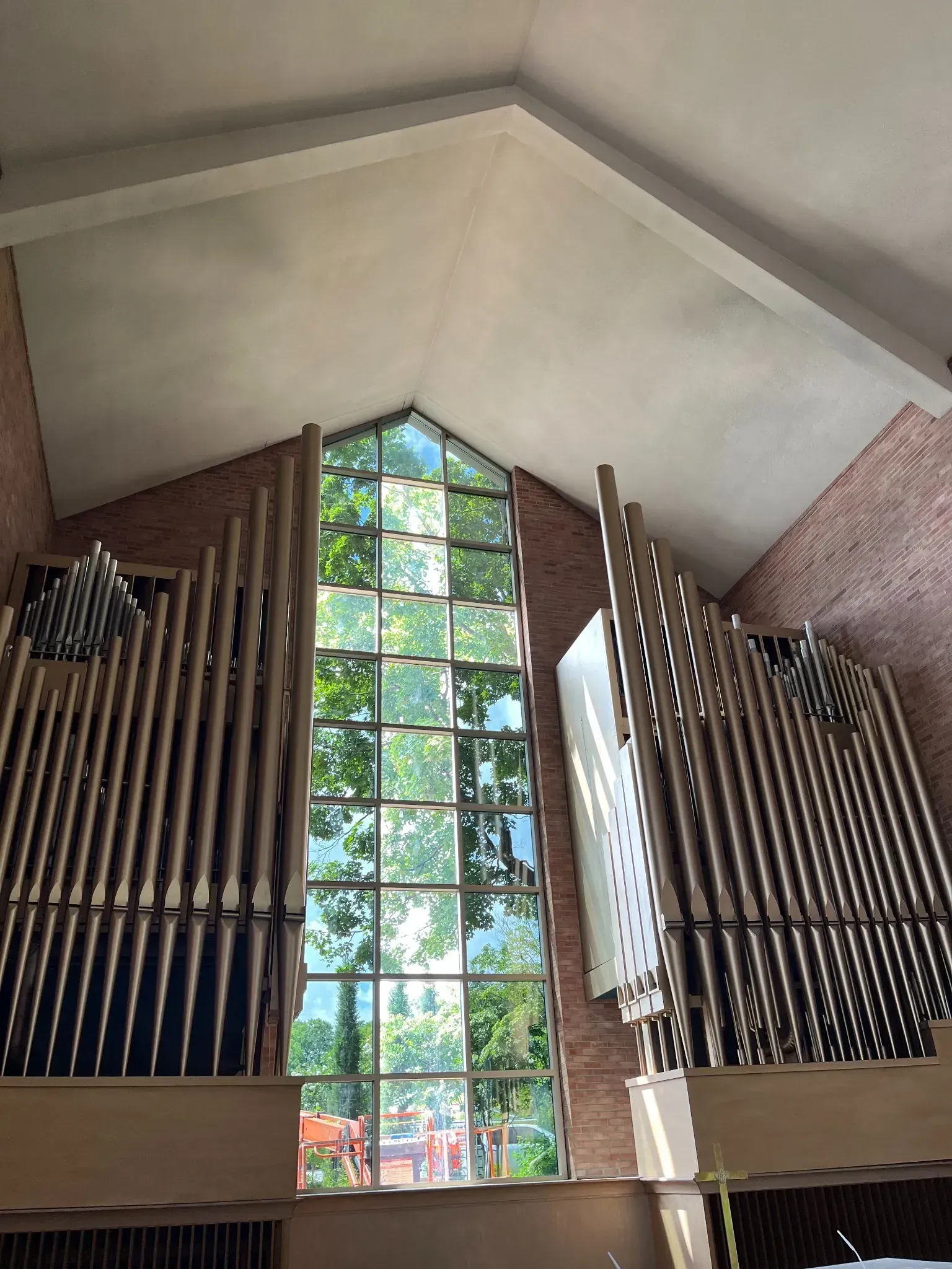 A large organ in a church with a large window behind it.