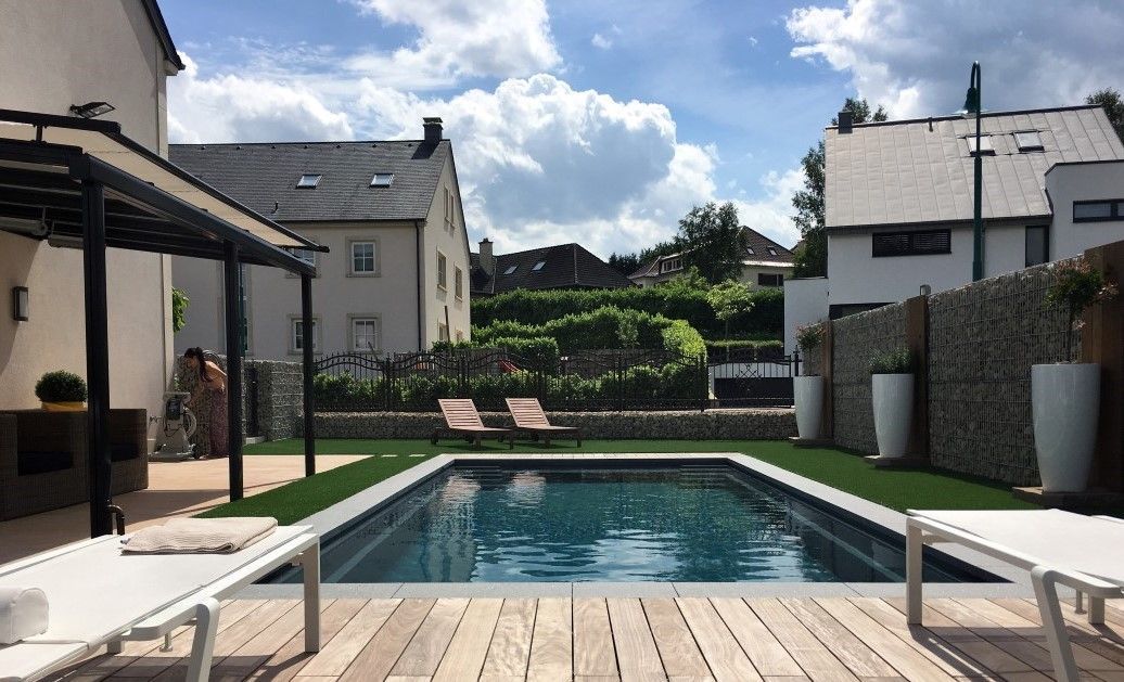 There is a large swimming pool in the backyard of a house.