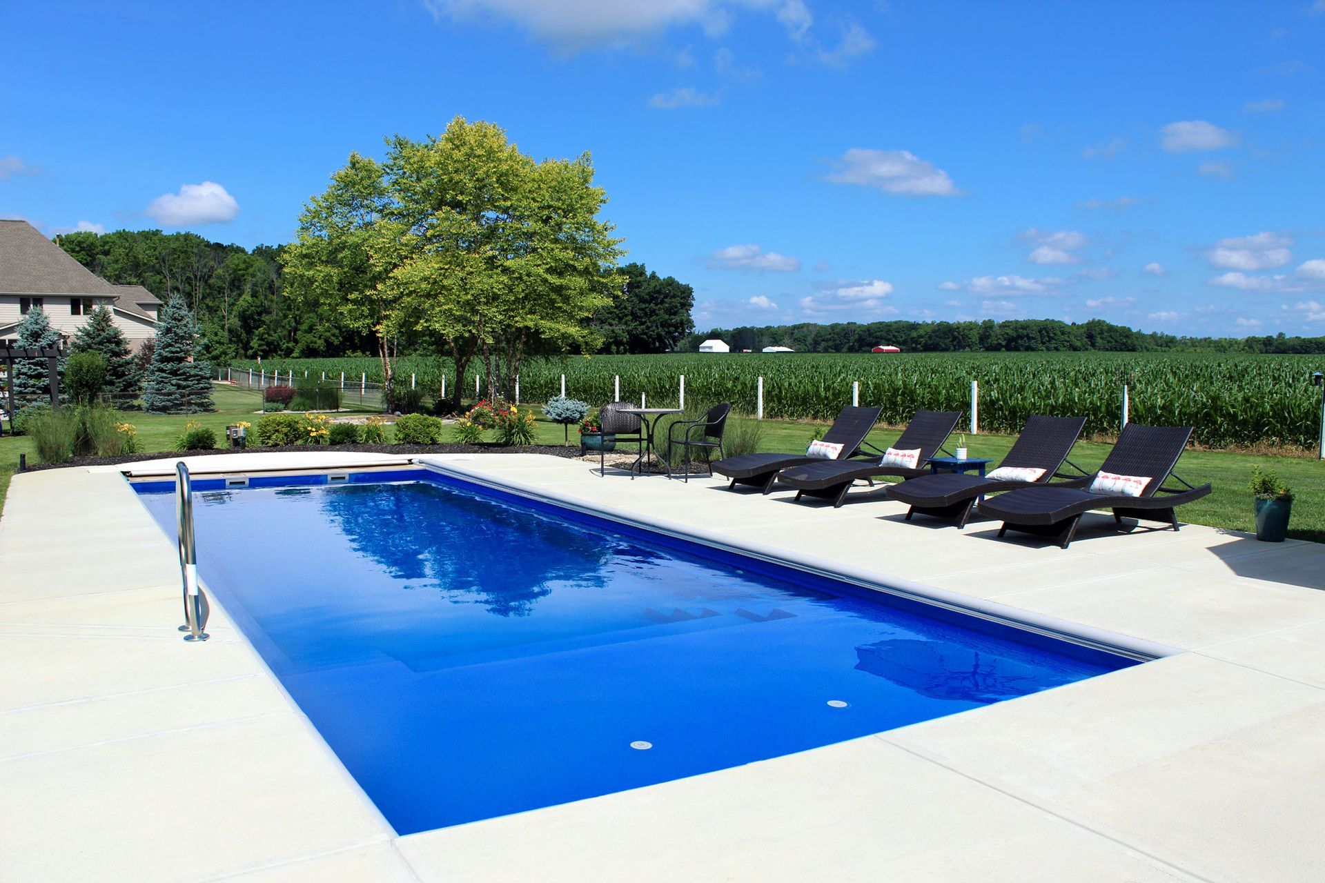 A large swimming pool surrounded by chairs and a field.