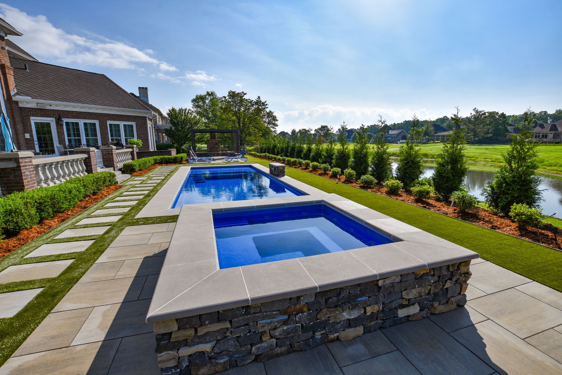 A large swimming pool and hot tub are in the backyard of a house.