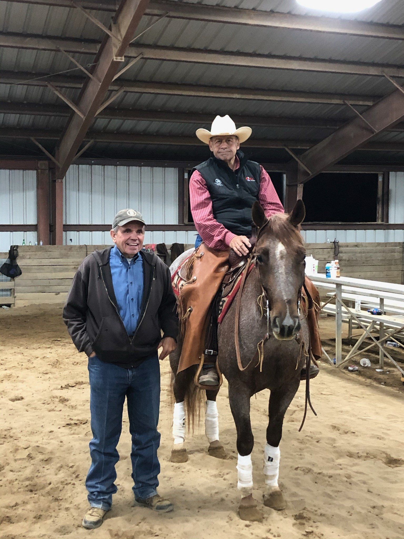 Bill Levering standing next to a man on a horse in a show arena
