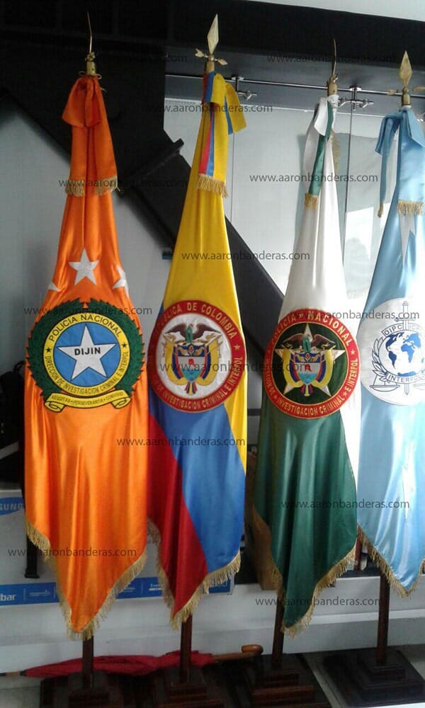 Cuatro banderas con emblemas están alineadas en fila.