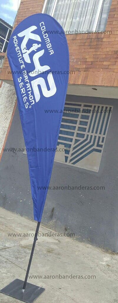 Una bandera azul en forma de lágrima se encuentra frente a un edificio.